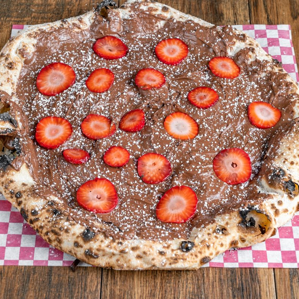 Blue Boy Pizza's dessert pizza with chocolate spread, sliced strawberries, and powdered sugar.