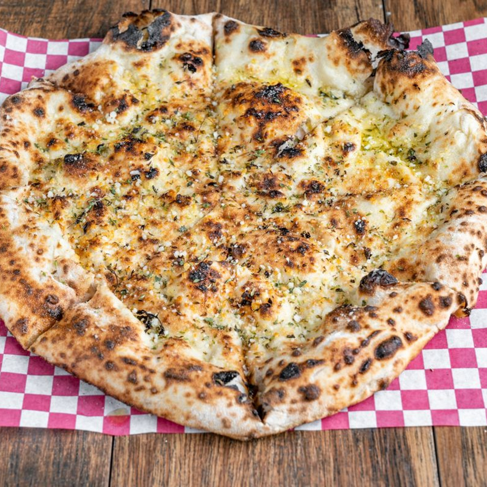 Blue Boy Pizza's garlic bread pizza, topped with herbs and cheese, on a red and white checkered paper.