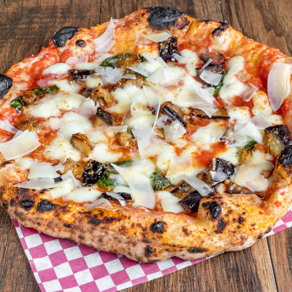 Blue Boy Pizza's eggplant and basil pizza, topped with shaved Parmesan, on a checkered napkin.